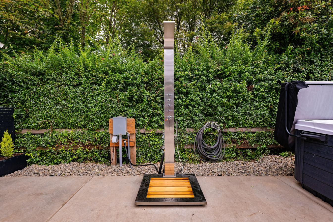 Outdoor shower with a teak floor mat