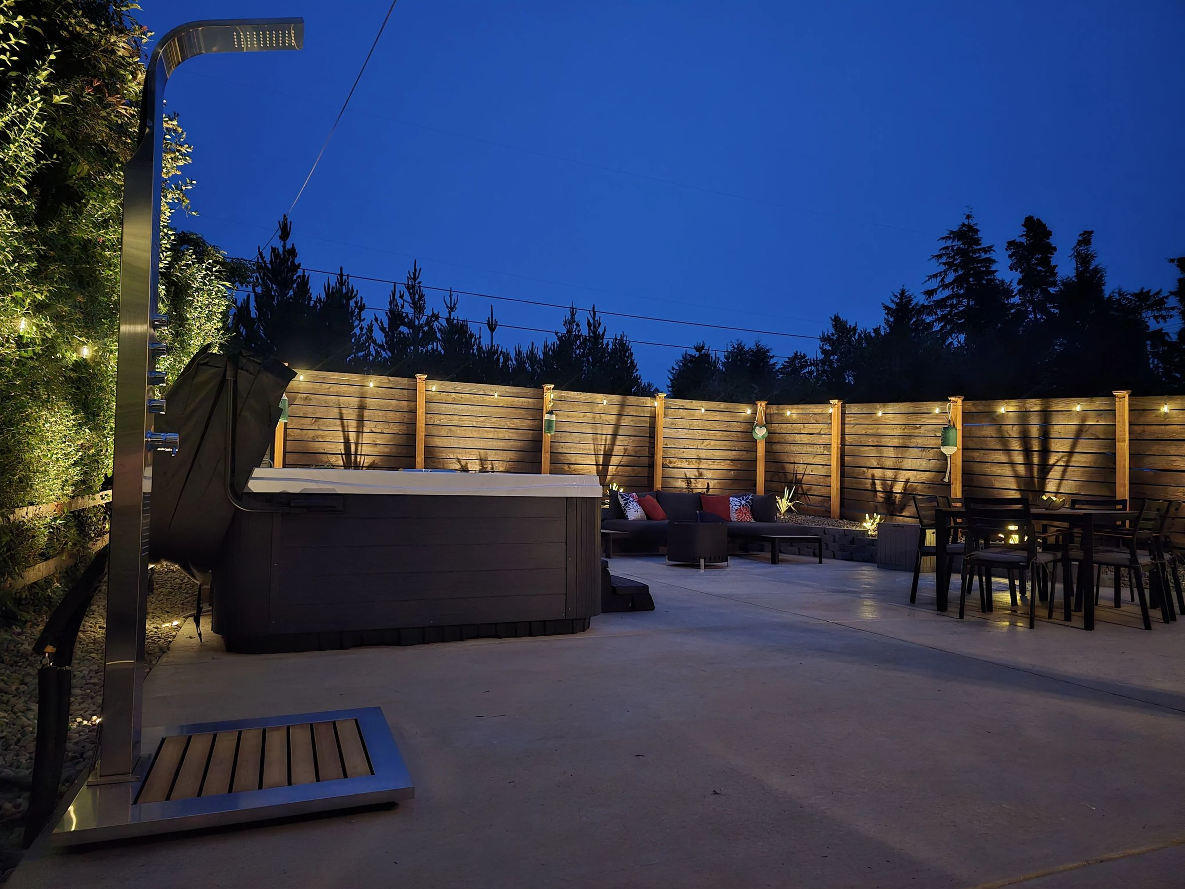 The courtyard at night: outdoor shower, hot tub, fire pit lounge and dining table