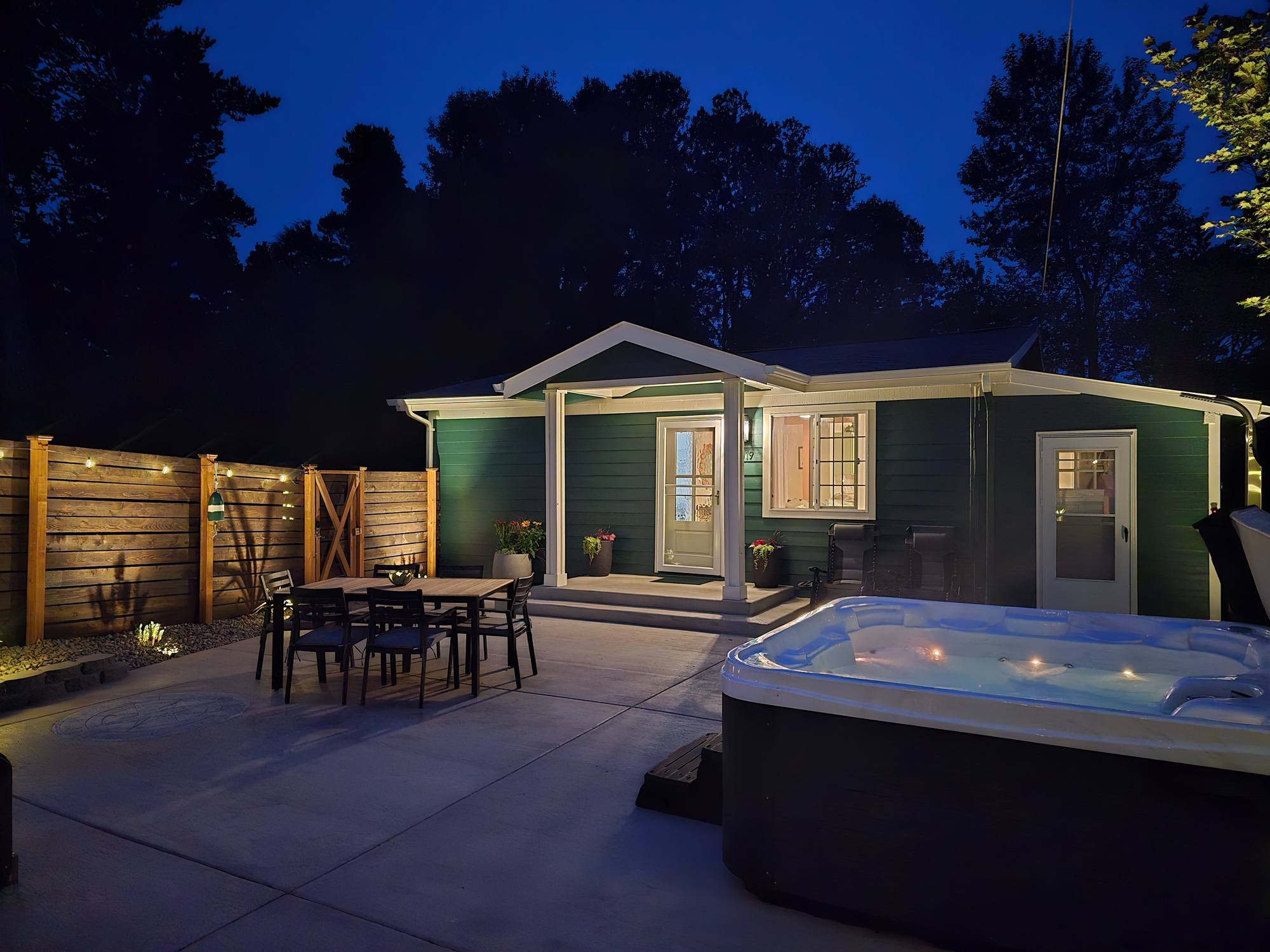The Resthouse at night: porch lit, dining table and hot tub in the courtyard