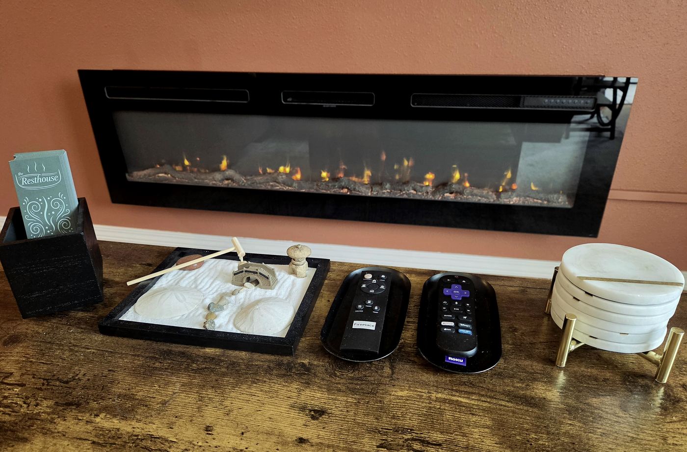 The living room fireplace lit, with the remotes on the table