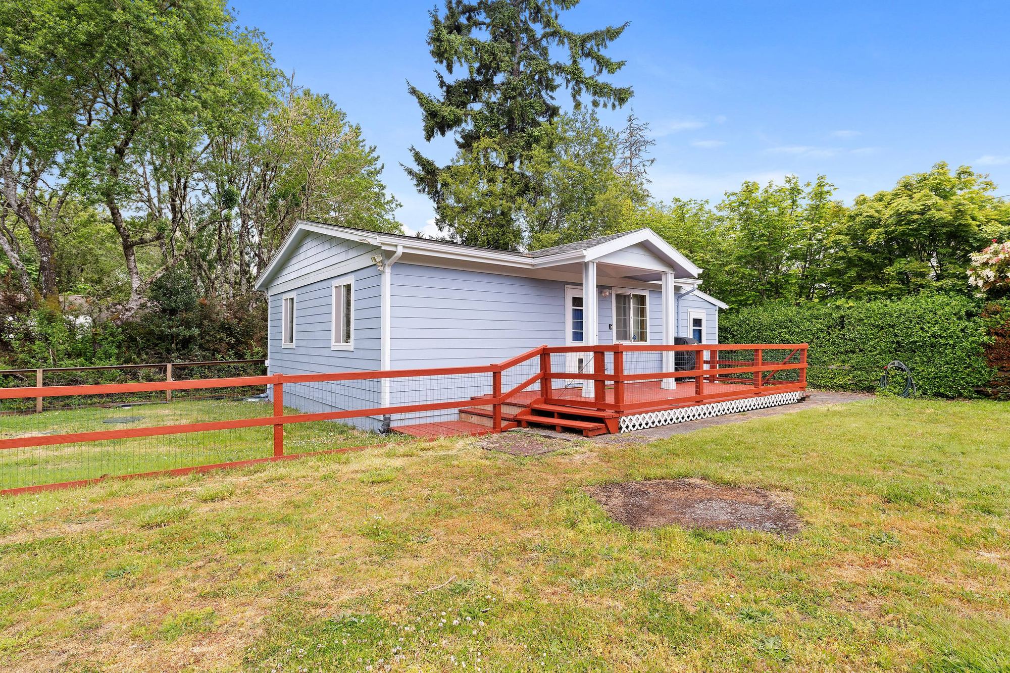 The Resthouse before renovation, May 2026: pale blue siding, red deck rail, open lawn